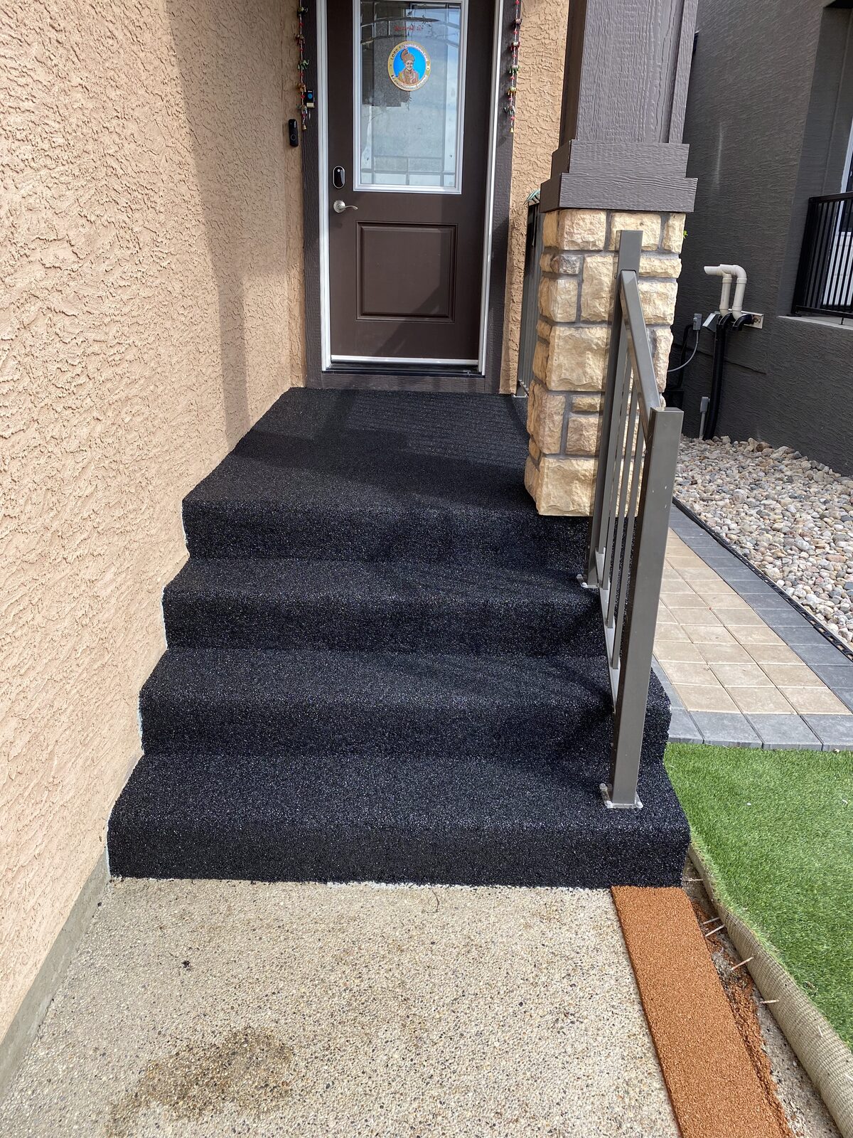 Black rubber front entry steps with a railing